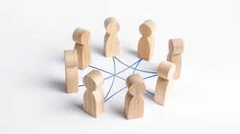 Photo of wooden figures connected by a blue grid network. 