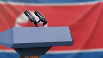 A microphone and podium with the North Korean flag in the background.